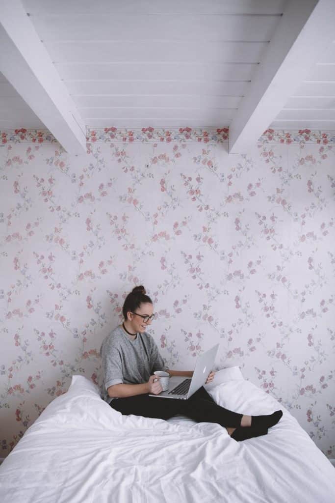 girl with a laptop sitting on a bed