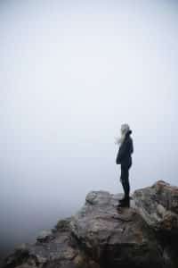 girl standing on cliff overlooking ocean